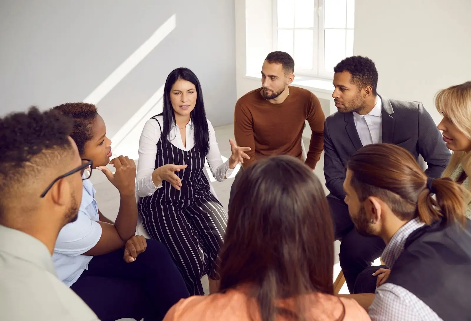 Group of people seated in a circle listening to one person speaking