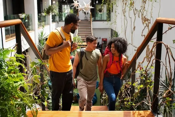 Three people smiling and conversing while climbing a staircase.